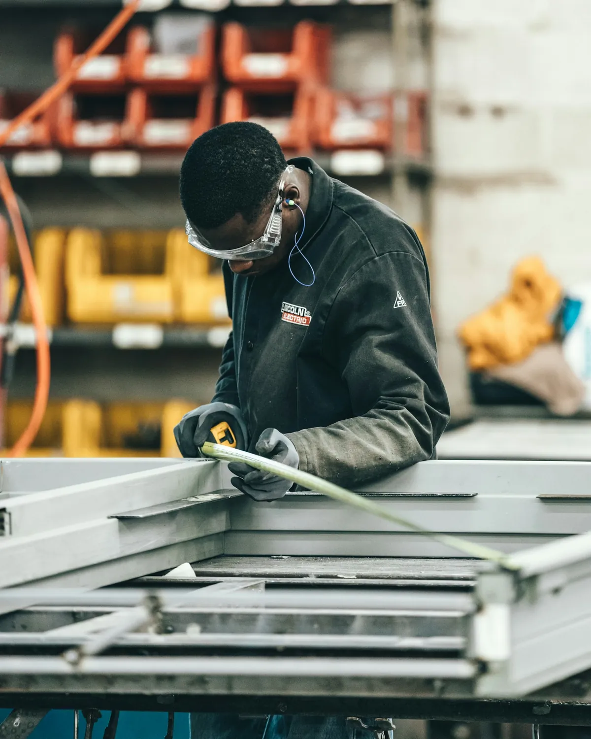 Worker measuring a steel frame in a workshop.